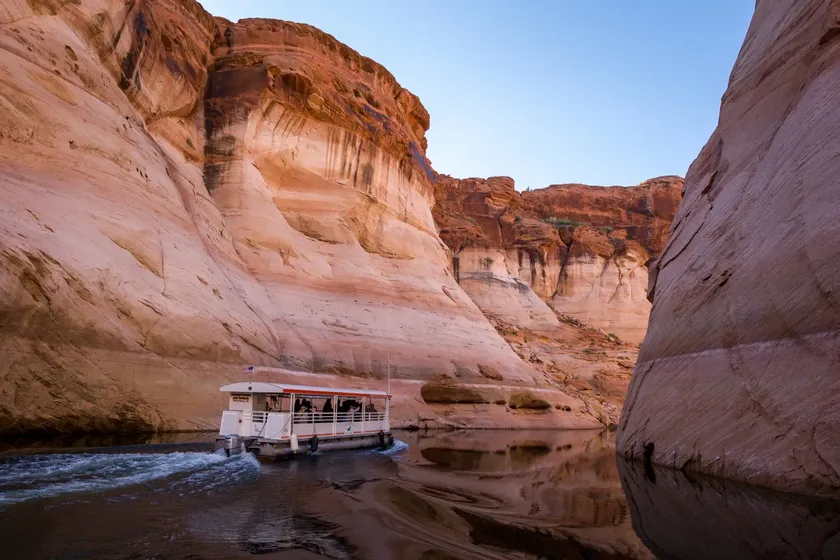 Tour boat cruising through towering pink sandstone walls of Antelope Canyon on Lake Powell