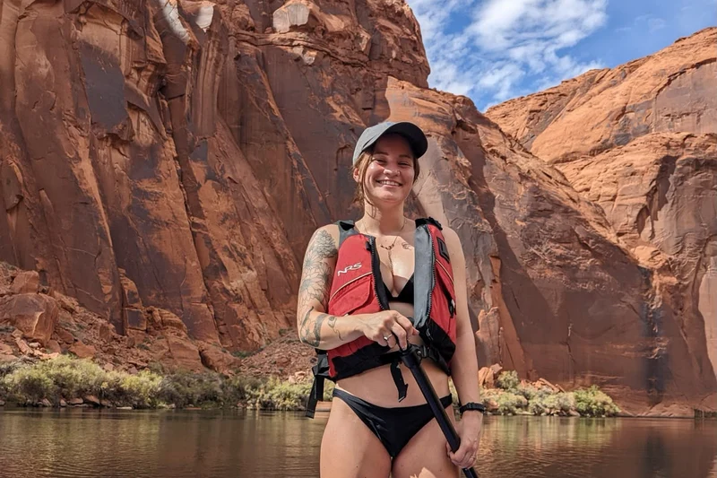 Paddleboarder on the Colorado River below red canyon walls